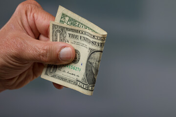 close-up of a man's hand holding a dollar bill / greenback