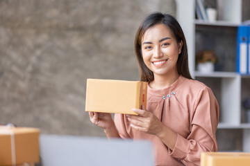 SME Online seller Young Asian woman working on laptop and box checking online order, check goods stock delivery package shipping postal. Asian woman startup SME small business at home office