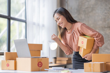 SME Online seller Young Asian woman working on laptop and box checking online order, check goods stock delivery package shipping postal. Asian woman startup SME small business at home office