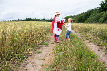 Two little girls on the field runs with the canadian flag