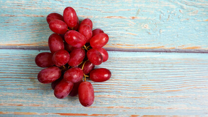 a bunch of pink grapes stands on a blue wooden table. view from above. grona grapes