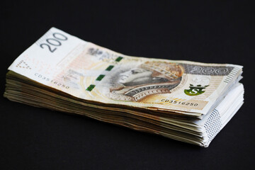 200 PLN . a stack of 200 zloty bills stands on a black background . side view .the currency of Poland. credit. purchase. cash