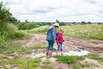 Obraz premium Two girls run through the puddles and play.