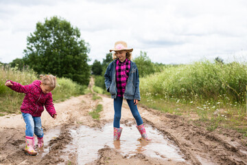 Two girls run through the puddles and play.