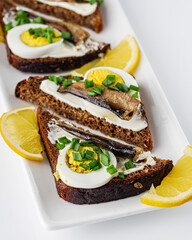 canapes with sprats on a white rustic wooden background