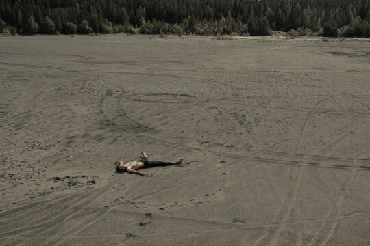 Lone Man lying on sand in desert