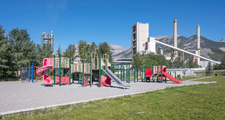 A playground with a cement plant in the background in the town of Exshaw