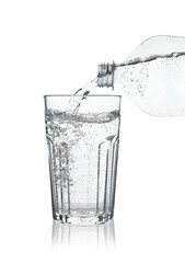 Pouring soda water from bottle into glass on white background