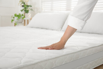 Woman touching soft white mattress on bed indoors, closeup - obrazy, fototapety, plakaty