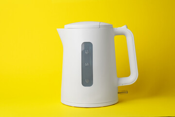 Modern plastic electric kettle on yellow background