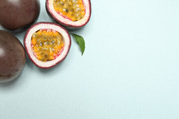 Fresh ripe passion fruits (maracuyas) with leaf on light background, flat lay. Space for text