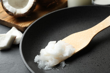 Frying pan with coconut oil and wooden spatula on table, closeup. Healthy cooking