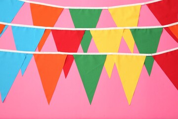 Buntings with colorful triangular flags on pink background. Festive decor