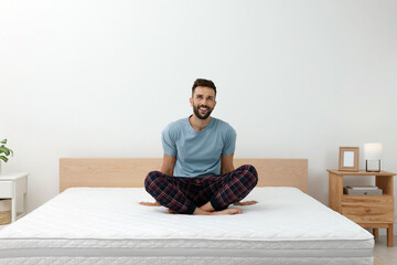 Happy man on bed with comfortable mattress at home