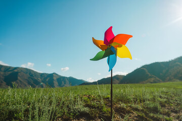 Symbol of clean green energy, pinwheel ibackground of the sky and a green landscape
