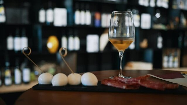 Glass of white wine and appetizer of mozzarella and ham.