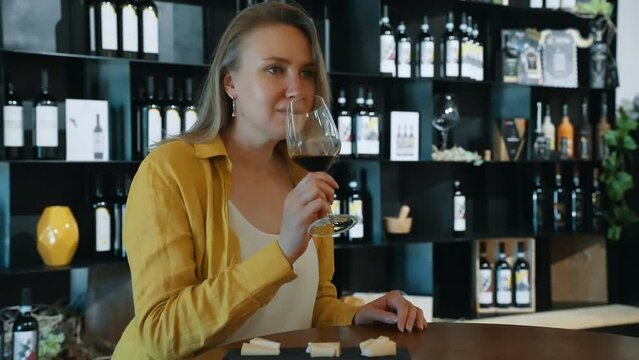 Woman is tasting red wine at a winery.