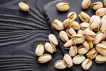 fresh salted pistachios on a black stone wooden rustic background