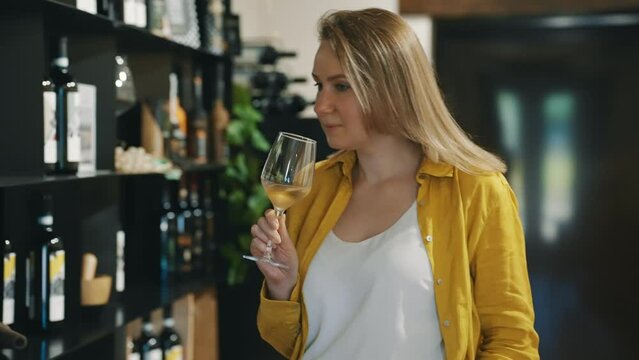 Woman is tasting white wine at a winery.