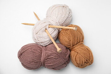 Fototapeta na wymiar Soft woolen yarns and knitting needles on white background, top view
