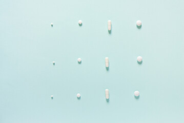Scattered white pills on blue table. Mock up for special offers as advertising, web background or other ideas. Medical, pharmacy and healthcare concept. Copy space. Empty place for text or logo