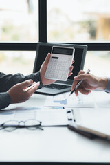 Two businessmen looking at sales data sheets in the office, they are business partners forming a startup company, are having a brainstorming meeting and planning an administration together.