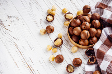 fresh macadamia nuts on a white wooden rustic background