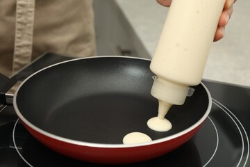Woman cooking cereal pancake on stove, closeup