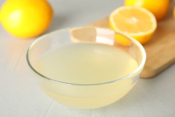 Obraz na płótnie Canvas Freshly squeezed lemon juice in bowl on light table, closeup
