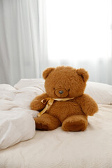 Ginger teddy bear sitting on the bed