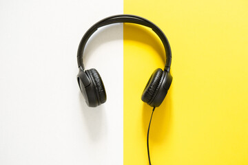 Hands holding headphones on a bicolor yellow and white background. view from above. copy space