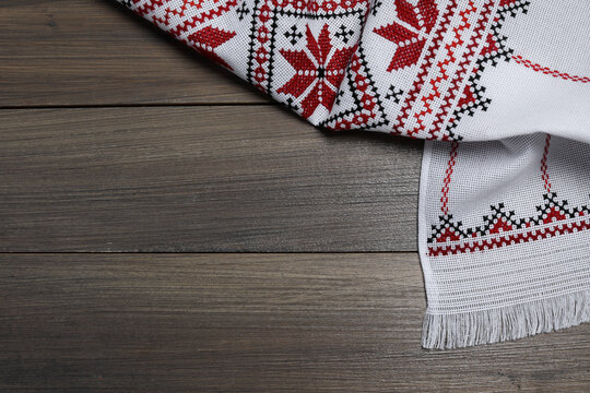 Beautiful rushnyk on wooden table, top view with space for text. Ukrainian national embroidery