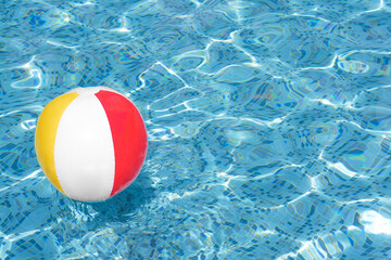 Inflatable beach ball floating in swimming pool, space for text