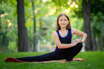 a little girl in the park performs stretching, stretching her squatting leg