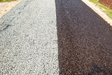New gravel road. Half road Pours liquid asphalt, molten bitumen from a bucket of resin.