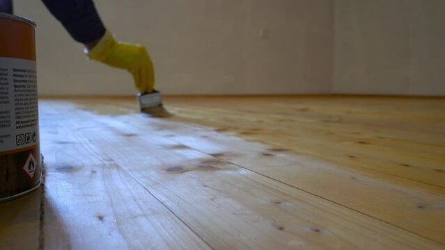 Manual coating of wooden floor with colorless varnish - (4K)