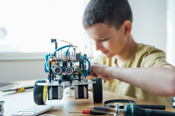 Close up shot of a young boy concentrating repairing his electronic robot toys while playing,...