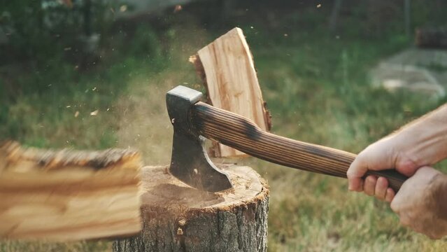Close-up guy chopping wood with an ax on a log. Spreads the shavings. Rest in a country house
