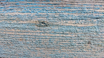 The texture of an old wooden board with traces of old cracked blue paint, traces of cracks and knots