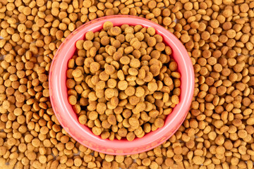 Pink bowl with dry food for a cat (dog) close-up. Balanced nutrition of pets.