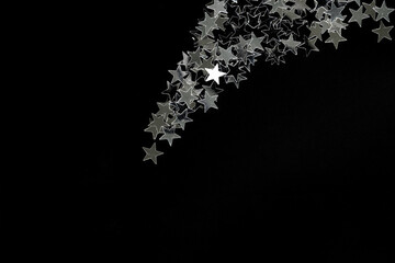 Falling down silver stars on a black background. The concept of a Christmas star and starfall. The concept of holiday magic and Christmas mystery. copyspace.