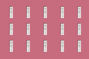 Positive Covid-19 antigen test pattern on pink background with harsh shadows © Yann Wirthor