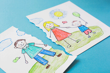 A torn children's drawing depicting a family is on a blue background. The topic of divorce of spouses and separation in the family.
