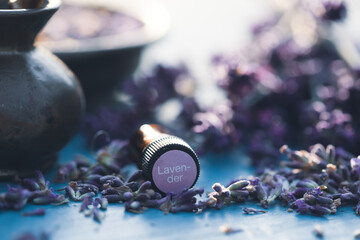 Bottle with aroma oil and lavender flowers on blue background