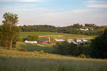 Fototapeta na wymiar Amish farm in a valley among the rolling hills of Holmes County farmland on a Summer afternoon