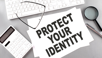 PROTECT YOUR IDENTITY text on paper with keyboard, calculator on grey background