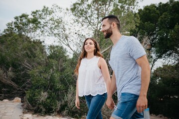 A Hispanic man and brunette woman are strolling in the highland park in Spain