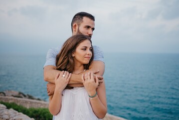 A man is hugging his girlfriend in the highland park near the sea in Spain