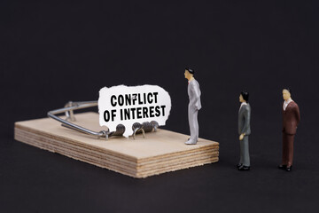 Figures of businessmen stand near a mousetrap, the bait in which is torn paper with the inscription...