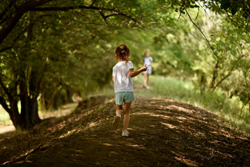 A girl in a white T-shirt runs under the trees. Nature. Backgroung. Beautiful.